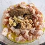 lime juice, olive oil, jerk seasoning and garlic on raw chicken in a bowl.