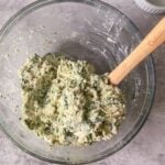 chicken, spinach, spices, eggs and cheeses mixed together in a bowl.