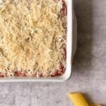cheesy red pasta in a dish ready to bake.