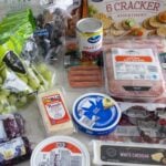 meats, cheeses, cranberries, and crackers on a table.