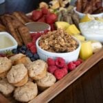 fruit, granola and bacon on a snack board.