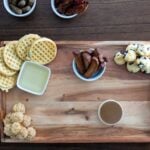 syrups, bacon and muffins on a charcuterie board.