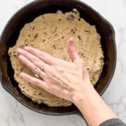 cookie dough being pressed into a skillet.