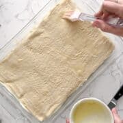 buttering an unbaked crescent roll sheet.