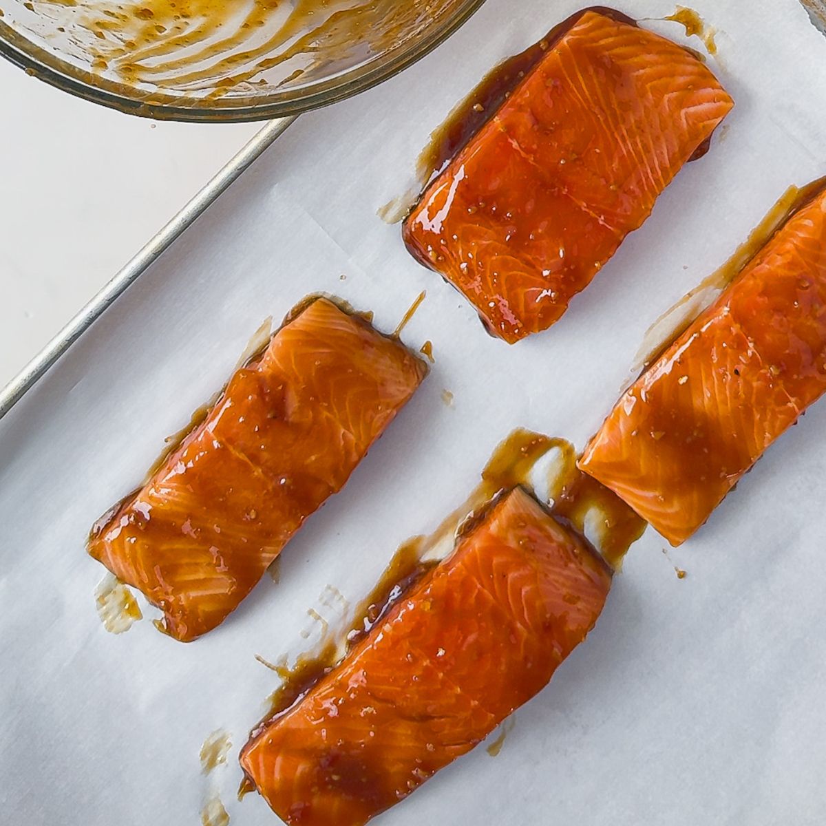 Adding the marinated salmon on the baking sheet.