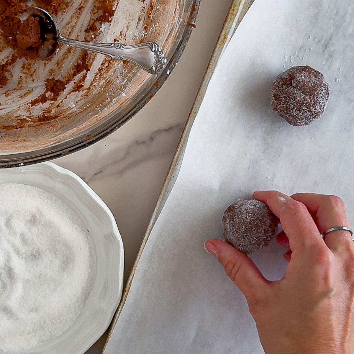 Adding dough balls to a parchment paper lined baking sheet.