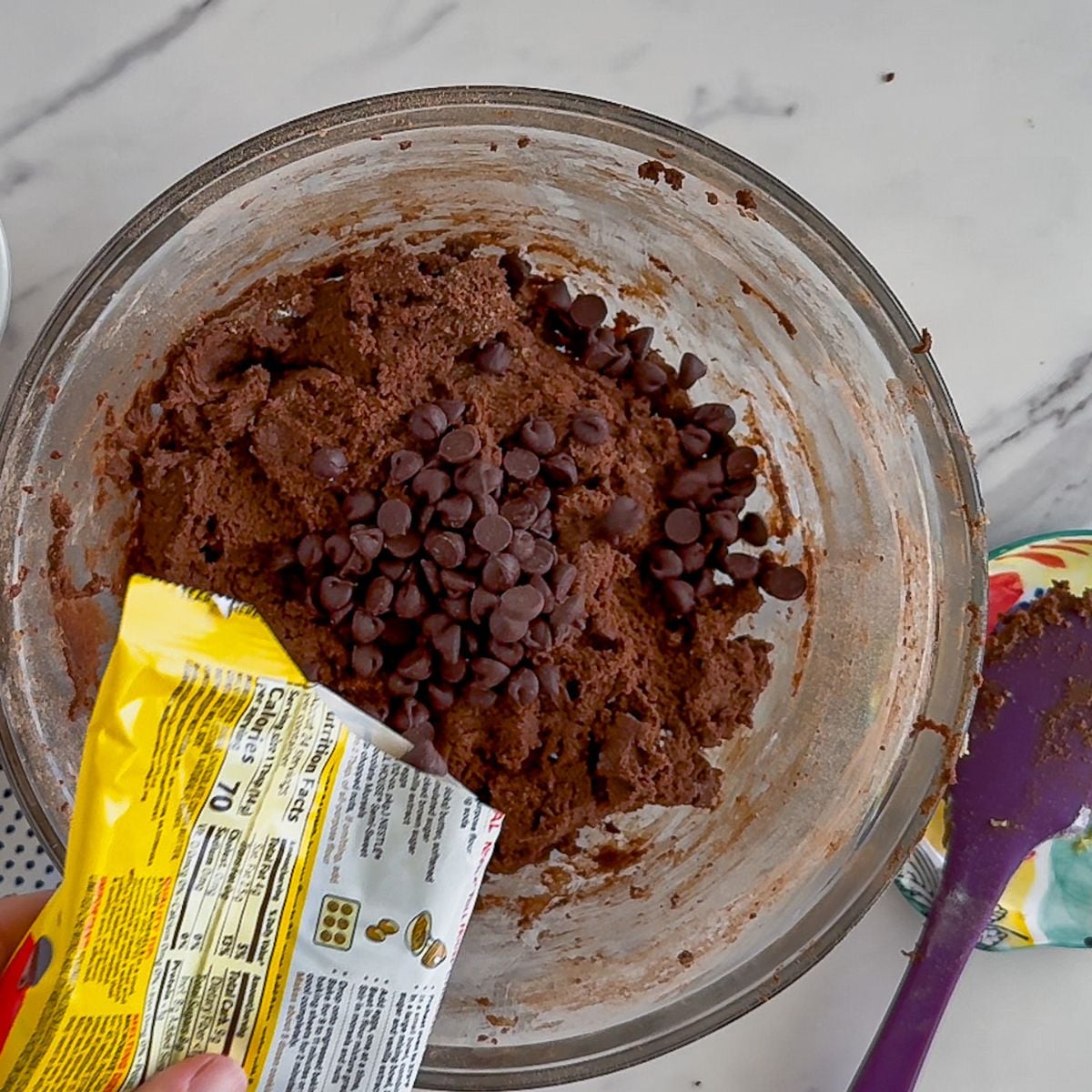 Pouring in the chocolate chips to the cookie dough.