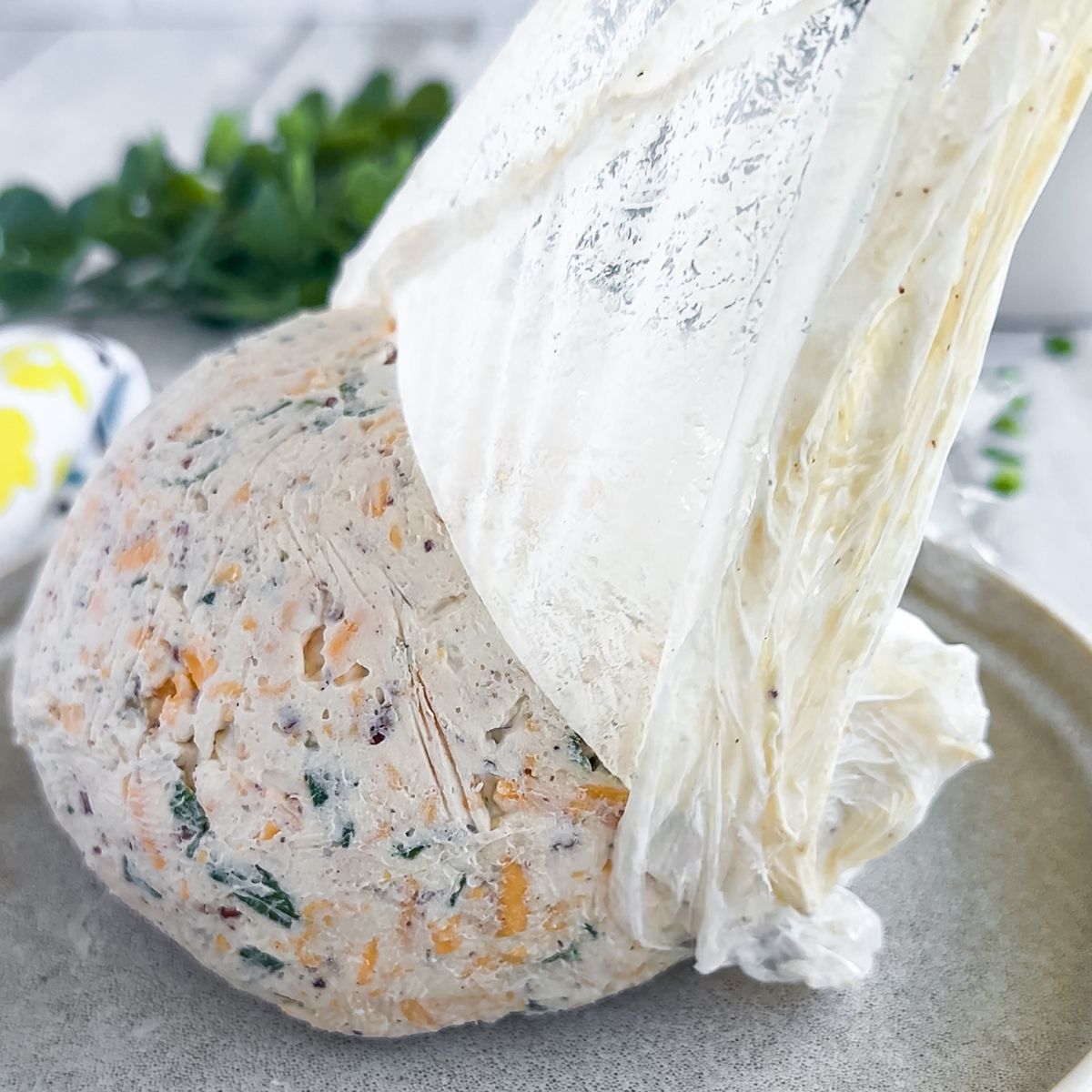 Removing the plastic wrap from the formed cheese ball.