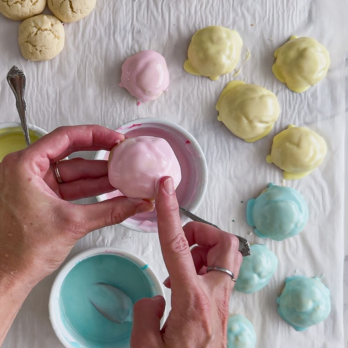 Dipping the cookies into the Easter pastel colored frosting.