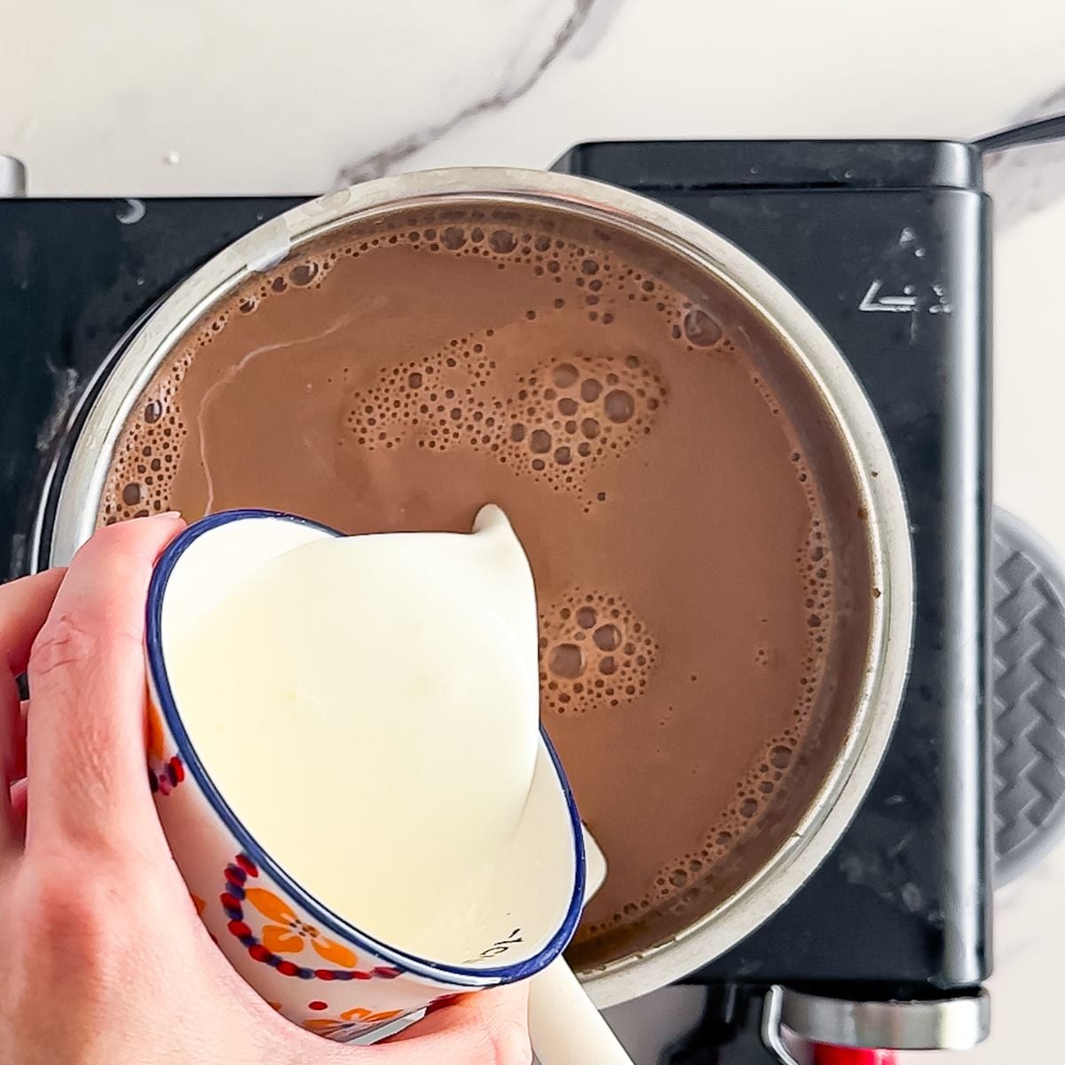 Adding in the cream and milk to the stovetop.