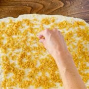 Sprinkling the orange roll filling onto the dough.