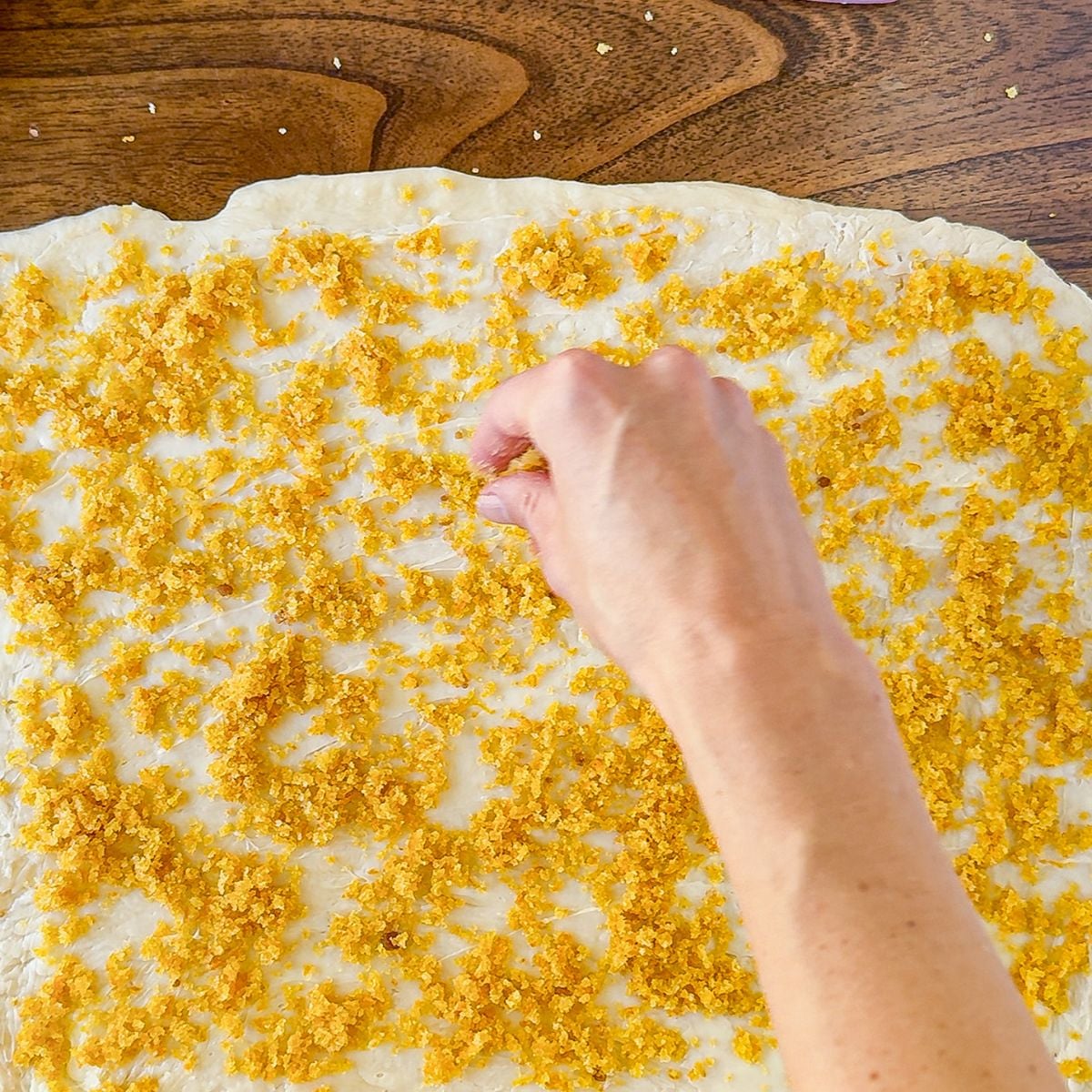 Sprinkling the orange roll filling onto the dough.