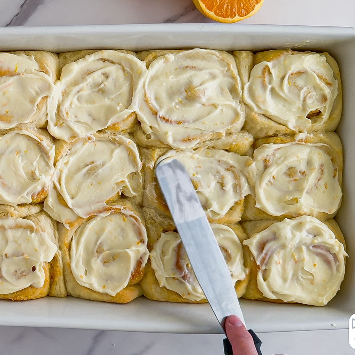 Spreading frosting on the rolls.