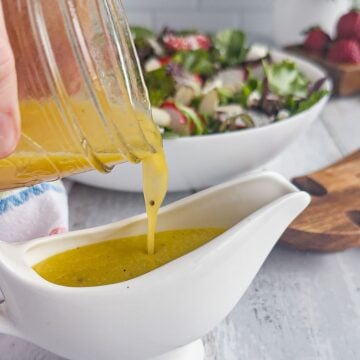 Pouring apple cider vinaigrette into salad dressing container.