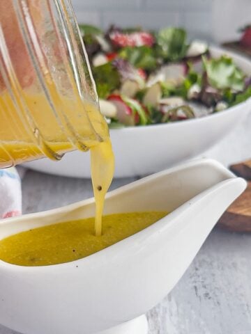 Pouring apple cider vinaigrette into salad dressing container.