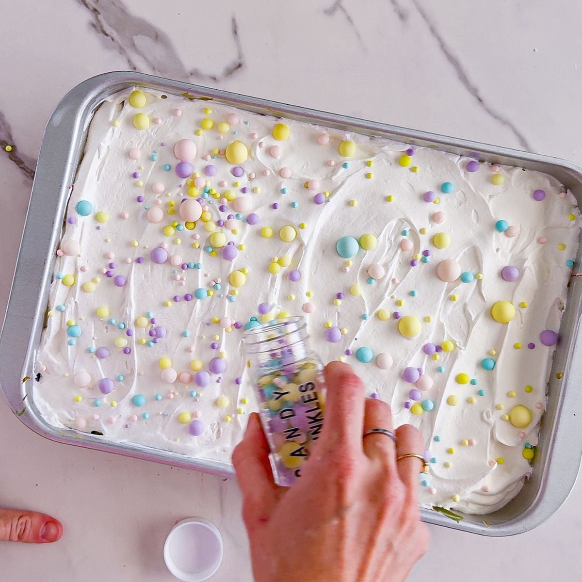 Adding sprinkles to poke cake.