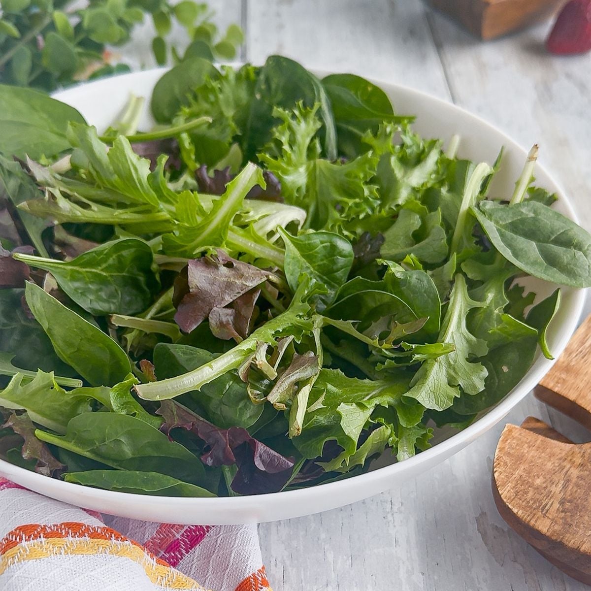 Adding greens to a bowl.