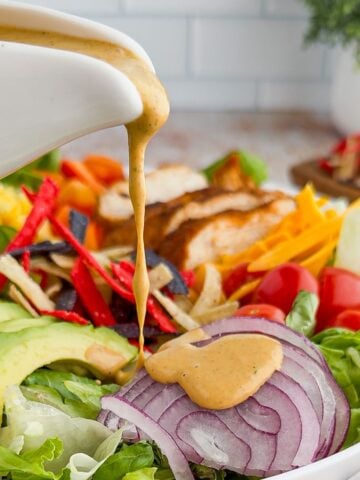 Pouring southwest dressing on a salad.