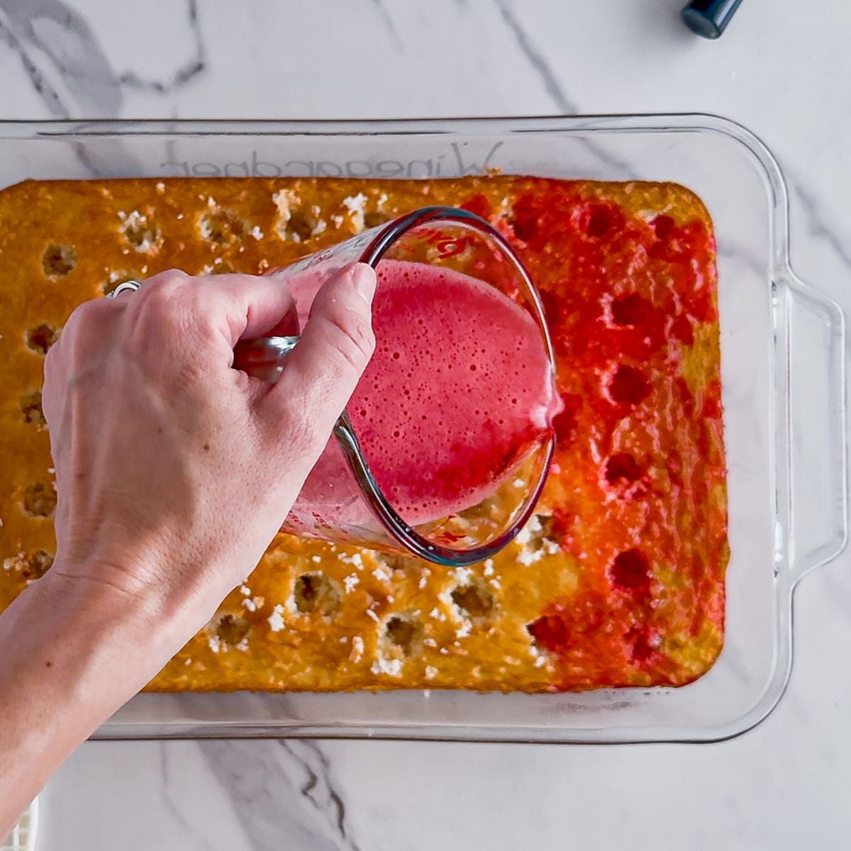 Pouring the jello into the cake.