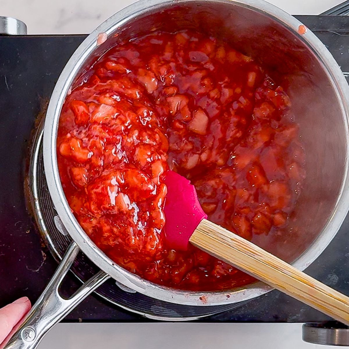 Stirring until the strawberries thicken.